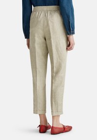 Pantalon beige clair avec un motif à carreaux subtil, taille élastique et ourlets roulés ; associé à des ballerines perforées rouges.