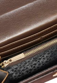 Brown leather handbag featuring a gold zipper closure, with a patterned black textile lining visible inside. Smooth texture and structured design.