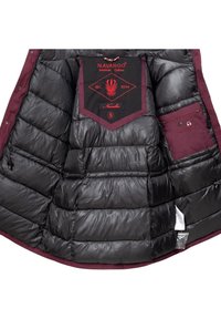 Indersiden af en sort pufferjakke med mørkerøde accenter, der har quiltet tekstur, mærker, en lille lomme og et kontrasterende mærkepatch.