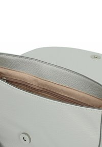 Interno di una borsa in pelle bianca con una finitura testurizzata, dotata di una tasca con zip beige e una chiusura a scatto con un accento argentato.