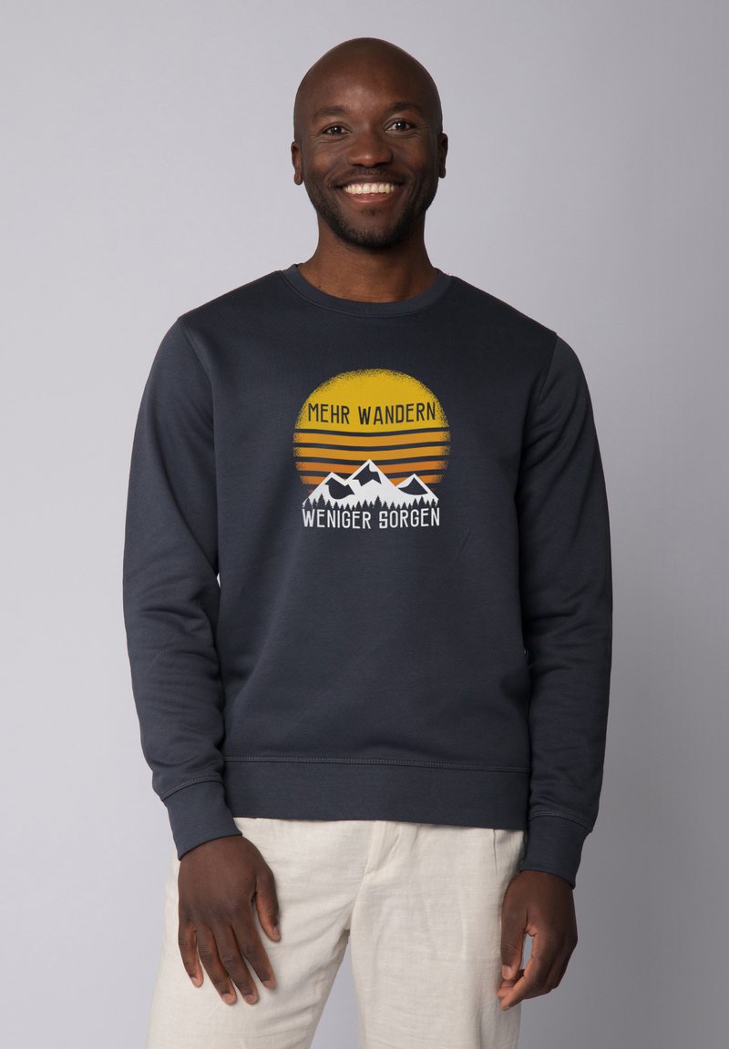 Navyblaues Sweatshirt mit langen Ärmeln und Rundhalsausschnitt, das ein grafisches Design von Bergen und einer Sonne in Gelb- und Orangetönen zeigt.
