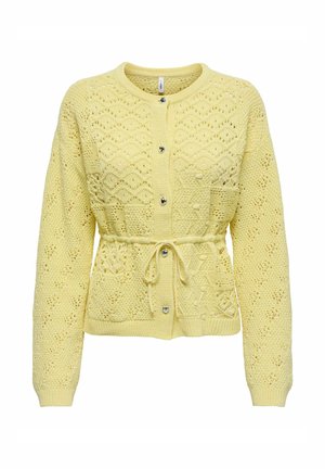 Valge kardigan kootud heledas kollases toonis, tekstuursete mustritega, pikkade varrukatega ja paelaga vööga. Omab nööpidega kinnitusi ja dekoratiivseid detaile.