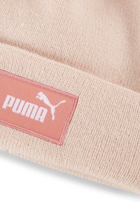 Ružičasti pleteni šešir s mekom teksturom, na kojem se nalazi pravokutna oznaka u koraljnoj boji s bijelim natpisom "PUMA" i siluetom.