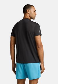 T-shirt sportivo nero a maniche corte con collo rotondo e tessuto testurizzato, abbinato a pantaloni corti azzurri, visto da dietro.