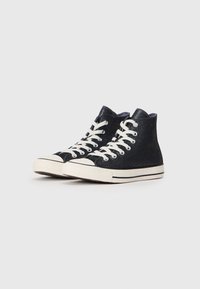 Adidași negri tip ghete, cu un sclipici subtil, șireturi albe, vârf din cauciuc și talpă clasică cu dungi. Material texturat și design cu guler înalt.