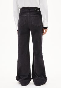 Svarta högmidjade vida jeans med en texturerad finish, stora bakfickor och en distinkt split på fållen.