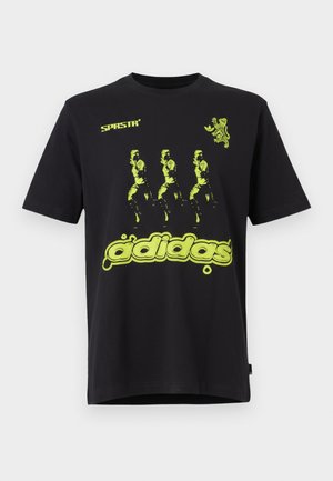 T-shirt di cotone nero con un vivace design grafico verde che presenta tre figure e il testo "adidas" in basso. Stile con collo a girocollo.