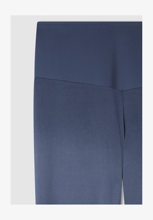 Leggings blu navy con una trama liscia e una vita alta. Il tessuto presenta una leggera lucentezza, affusolandosi verso la caviglia.