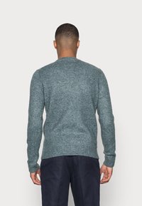 Pull en tricot bleu-vert chiné, col rond, finitions côtelées, tissu texturé. Conçu avec des manches longues et une coupe décontractée.