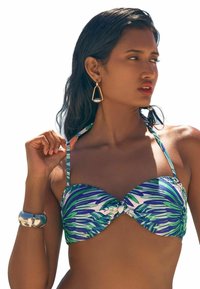 Bikini viršus su mėlyno ir žalio lapo raštu, struktūruotais puodeliais ir reguliuojamomis petnešėlėmis. Į komplektą įeina sidabrinė apyrankė ir auksinės auskarai.