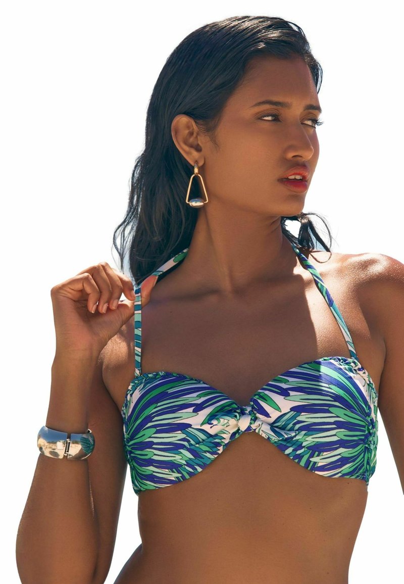 Bikini viršus su mėlyno ir žalio lapo raštu, struktūruotais puodeliais ir reguliuojamomis petnešėlėmis. Į komplektą įeina sidabrinė apyrankė ir auksinės auskarai.