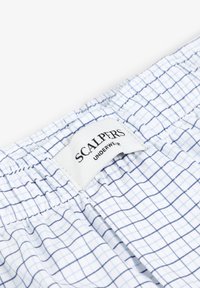 Boxers à carreaux blancs et bleus avec ceinture élastique arborant une étiquette "SCALPERS UNDERWEAR". Fabriqués en coton léger.