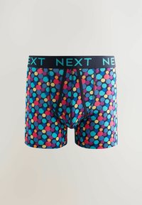 Un boxeur avec un fond bleu marine et des pois multicolores. Ceinture élastique noire avec "NEXT" imprimé en turquoise. Tissu doux.