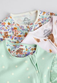 Három NEXT bababody pasztell színű, virágos, állatmintás és pöttyös mintákkal, fehér háttéren egymásra rétegezve.