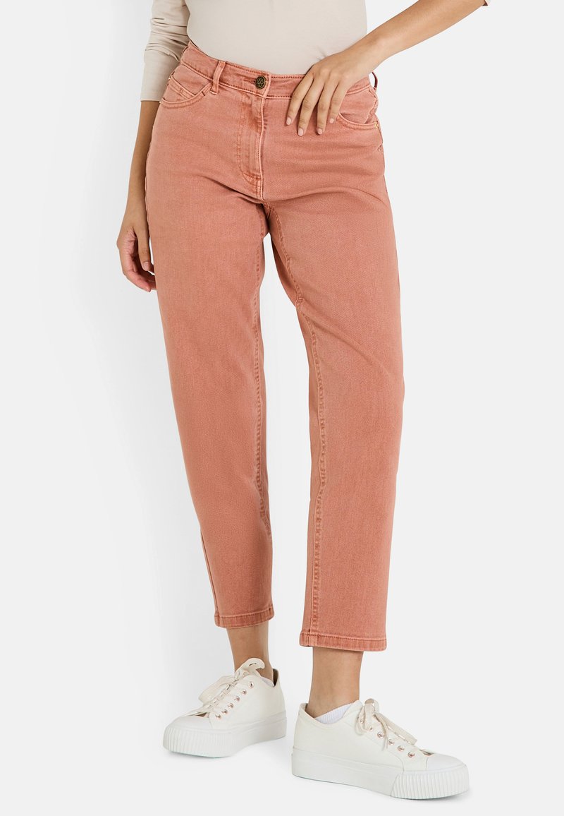 Jean taille haute couleur rouille avec coupe droite, comportant cinq poches, fermeture à bouton et texture légère, associés à des baskets blanches.