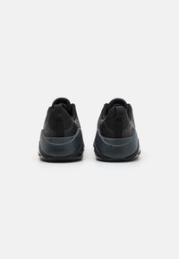 Scarpe da ginnastica nere con tomaia testurizzata, tallone grigio scuro a contrasto, linguette per il tiro a forma di anello e decorazioni a motivo. Suola in gomma per la trazione.