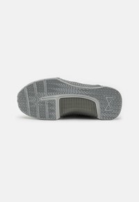 Gray athletic shoe sole with textured rubber, zigzag pattern, and a semi-transparent section near the heel; features branding.