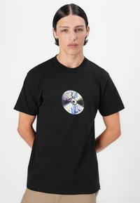 Black cotton t-shirt featuring a circular graphic design resembling a CD with colorful text and illustrations. Short sleeves, crew neck.