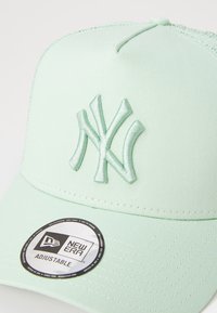 Menta zöld sapka hímzett NY logóval, struktúrált kialakítással és állítható snapback pánttal. A karimáján kör alakú címke található.