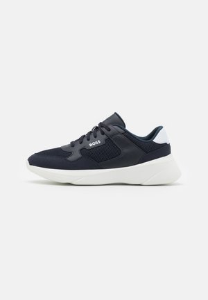 Baskets BOSS noir et blanc avec tige en mesh et cuir, design à lacets et semelle blanche épaisse visibles de profil sur fond blanc.