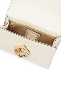 Μπεζ δερμάτινη τσάντα χειρός με χρυσό γεωμετρικό κλείσιμο λογότυπου. Διαθέτει επενδεδυμένο εσωτερικό με τσέπη φερμουάρ και ετικέτα επωνυμίας ορατή στο εσωτερικό.