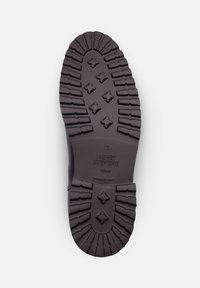 Semelle de chaussure en caoutchouc noir avec des motifs de semelle profonds, comportant un logo de marque et des détails du modèle. Surface texturée pour une adhérence et une durabilité optimales.