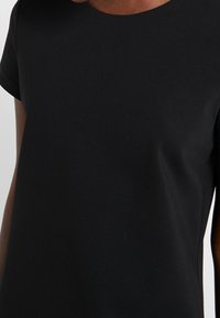 Svart kortärmad t-shirt i slät tyg, med rund hals och en avslappnad passform, i en solid, enhetlig färg genomgående.