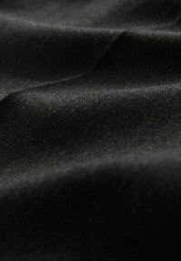 Sort stof med et struktureret fiskebenmønster, der har bløde folder og en glat finish. Tekstilet har et dybt, mørkt udseende.