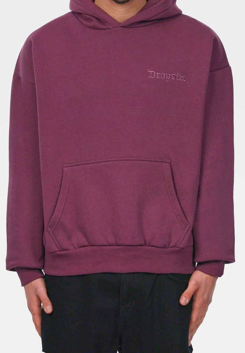 Homme portant un sweat à capuche bordeaux avec poche kangourou à l'avant et "Dropsize" brodé sur la poitrine.