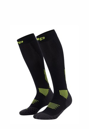 Schwarze Kompressionssocken mit strukturierten Mustern in Neon-Gelb. Knielanges Design mit geripptem Effekt, Silikon-Grip und verstärktem Zehenbereich.