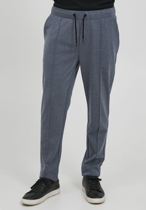 Lette grå stretchbukser med snøring i livet, med to sidesømmer, kombinert med svarte joggesko.