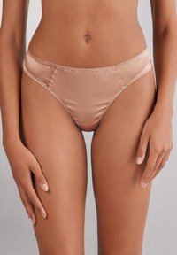 Satinowe majtki bikini w kolorze nude, o gładkiej fakturze, elastycznym pasie i wysokim kroju dla lepszego dopasowania.