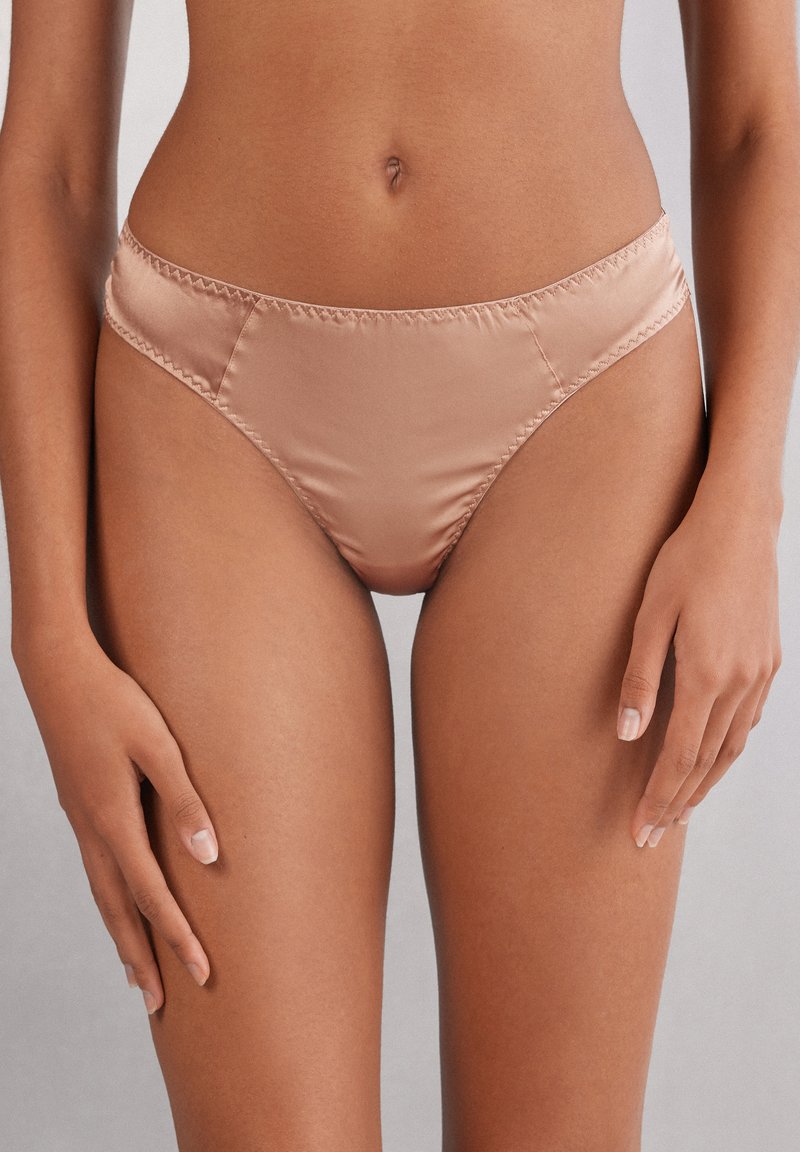 Satinowe majtki bikini w kolorze nude, o gładkiej fakturze, elastycznym pasie i wysokim kroju dla lepszego dopasowania.