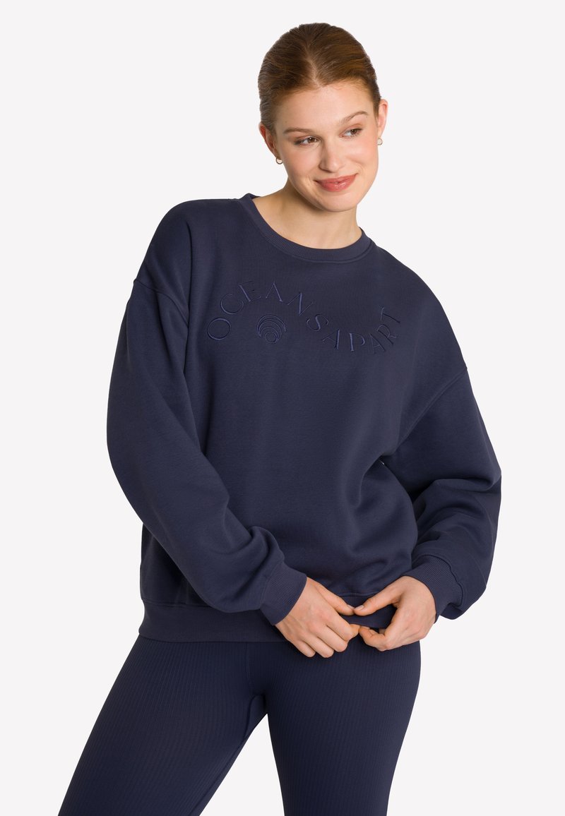 Marineblaue Sweatshirt mit lässigem Schnitt, rundem Halsausschnitt und geprägtem Logodetail. Der Stoff fühlt sich weich an und hat eine strukturierte Oberfläche.