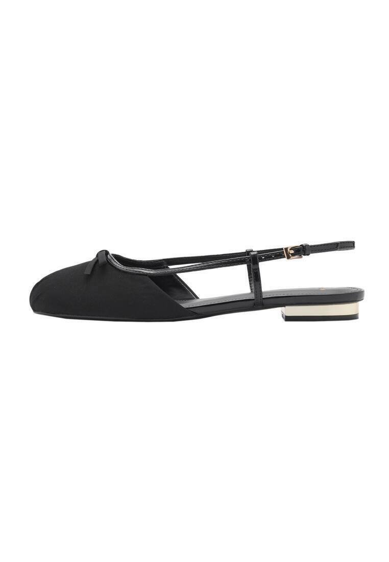 Black ballet flats with a pointed toe, flat heel, fabric upper, ankle strap, and bow detail. Features a contrasting metallic heel accent.