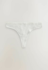 Bijela pamučna tanga gaćice s minimalnim dizajnom, koje imaju tanke elastike i bočne strane, glatku teksturu te bez vidljivih uzoraka ili naglasaka.
