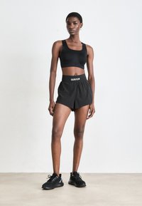 Completo di top sportivo nero e pantaloni sportivi con logo Calvin Klein. I pantaloni presentano un elastico in vita e una vestibilità morbida. Scarpe da ginnastica nere completano il look.