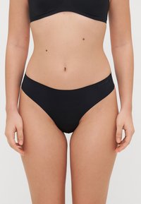 Black bikini briefs made of smooth fabric, featuring a low-rise waist and minimal stitching. Accented with a subtle logo on the waistband.