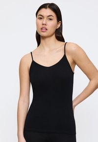 Camisola nera aderente con spalline sottili, scollatura a V, realizzata in tessuto morbido, che mostra un design senza cuciture e una silhouette aderente.