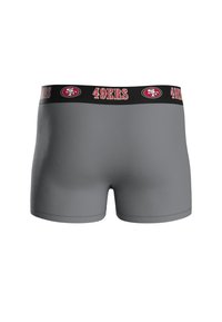 Boxers grises ajustados con una cinturilla de logo negra que presenta "49ERS" y un emblema estilizado. Textura suave, forma ceñida y corte de longitud media.