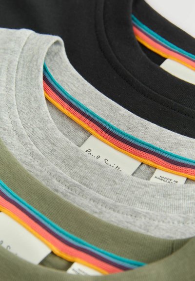 Quattro t-shirt con scollo rotondo in grigio, oliva e nero, con accenti colorati e testurizzati sul collo. Etichette visibili sul retro.