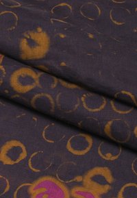 Tessuto in cotone di colore viola scuro, caratterizzato da motivi circolari astratti in giallo oro e fucsia, dal tatto morbido e liscio.