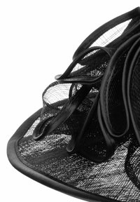 Black wide-brim hat made of mesh, featuring layered swirls and a satin band along the edge. Textured and semi-transparent design.