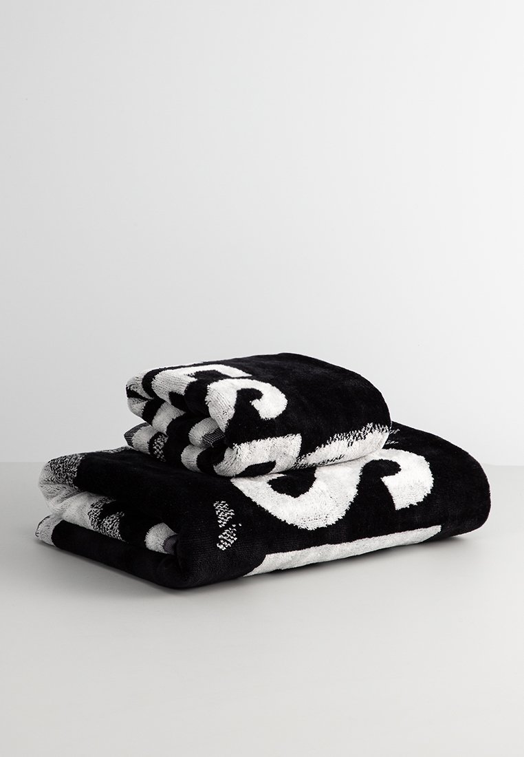 Serviettes noires et blanches empilées, arborant un motif tourbillonnant en tissu en coton moelleux. Texture douce avec des couleurs contrastantes et un design audacieux.