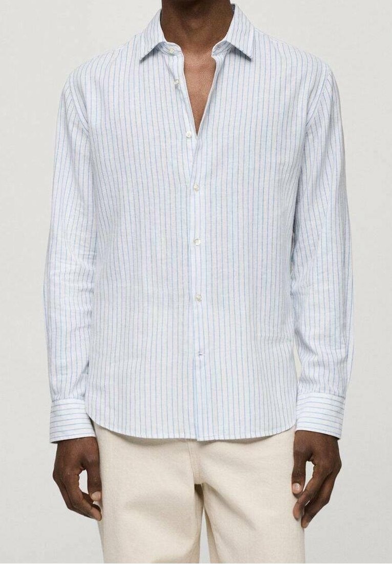 Jasnoniebieska, w paski, koszula z długim rękawem, wykonana z lekkiego materiału, z kołnierzykiem zapinanym na guziki i prostym dołem. Guziki są białe.