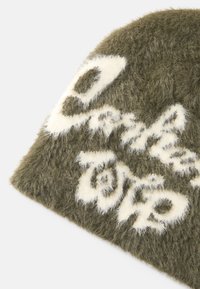 Olivgrüner, flauschiger Strickbeanie mit cremefarbenem Textmuster. Runde Form mit weicher Textur und sichtbaren Nähdetails.