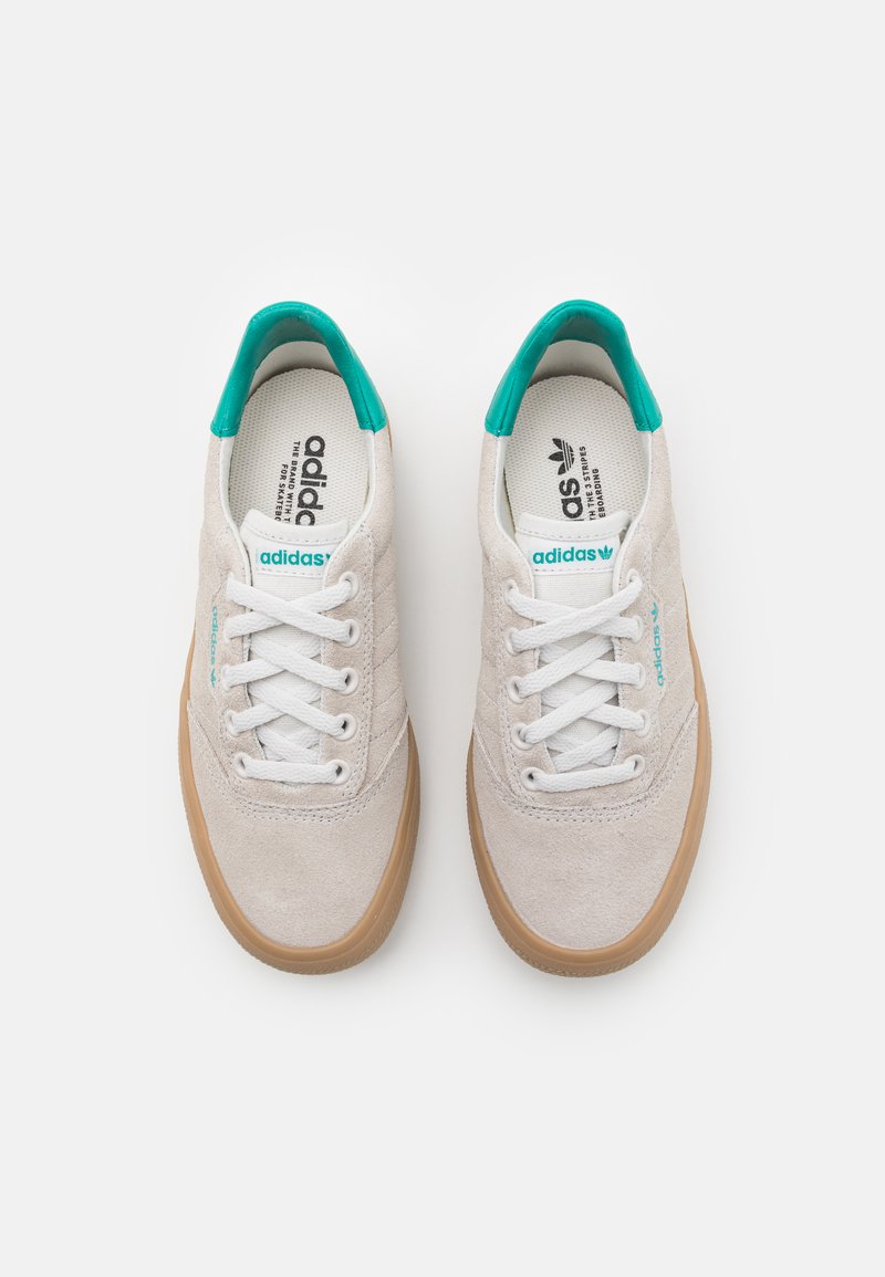 Baskets en daim blanc avec des semelles en caoutchouc naturel, des accents turquoise et des lacets blancs. Comprend une semelle intérieure marquée et des détails de logo.