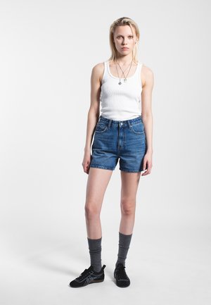 Niebieskie dżinsowe szorty z wysokim stanem i mankietami, biały prążkowany top na ramiączkach, szare skarpetki do kolan oraz czarne trampki z niebieskimi akcentami. Prosty design.