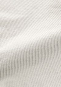 Tessuto bianco a coste, superficie texturizzata con morbide righe, che presenta una piega liscia e uniforme, adatto per abbigliamento o tessuti per la casa.