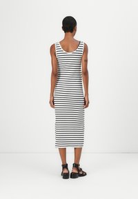 Striped tank dress in black and white, ribbed material, midi length, scoop back, worn with black strappy sandals featuring block heels.